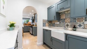 Uma cozinha moderna com armários cinza, bancada branca e painel de azulejos.