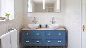 Une salle de bain avec deux lavabos blancs, un meuble-lavabo bleu et un miroir au-dessus.