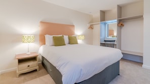 Une chambre à coucher avec un grand lit, deux tables de chevet, une commode, une fenêtre donnant sur un beau paysage et une armoire.