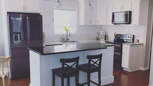 A modern kitchen with white cabinetry, a stainless steel refrigerator, a microwave, and a coffee maker. - 3 bedroom, 2 bath luxury home a stones throw from Thames (Newport)