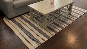 A living room with a grey sofa, a wooden coffee table, and a striped rug. - 3 bedroom, 2 bath luxury home a stones throw from Thames (Newport)