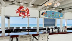 A bar with a view of the ocean, featuring a crab logo and a menu board. - Destin Crystal Beachside Escape~Steps to Beach & Pool~Prime location (Destin)