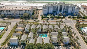 An aerial view of a coastal hotel with multiple buildings, a swimming pool, and a beach in the background. - Destin Crystal Beachside Escape~Steps to Beach & Pool~Prime location (Destin)