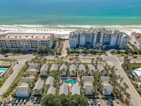 An aerial view of a coastal hotel with multiple buildings, a swimming pool, and a beach in the background. - Destin Beachside Escape~Steps to Beach & Pool~Prime location, Crystal Beach (Destin)