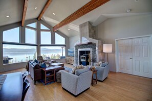 Relax in this inviting space with a stone fireplace, comfortable seating, and a view of the water and distant mountains.
