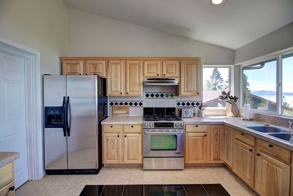 Enjoy a scenic view from the large window in this kitchen, which features a refrigerator, oven, microwave, and toaster.