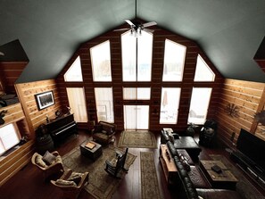 Ein großzügiger Loft-Raum mit schrägem Dach, großen Fenstern und Deckenventilator.