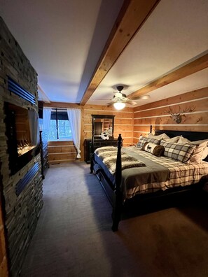 Ein schlafzimmer im Chalet-Stil mit einem Himmelbett, einem hölzernen Deckenventilator und einem Hirschgeweih an der Wand.