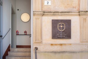 Eine Treppe führt zu einem Raum, in dem eine Plakette "Dimora del Vescovo GUESTHOUSE" aufgestellt ist.