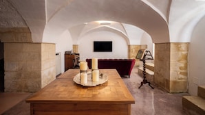 Una habitación acogedora con una mesa de madera, velas y un sofá rojo.