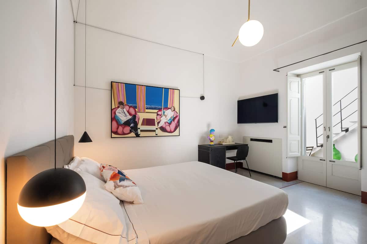 Una habitación de hotel moderna con una cama grande, un escritorio, una silla, un televisor y una escalera.