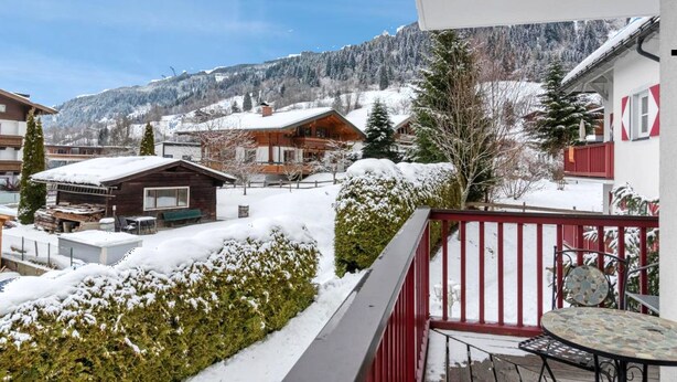 A snow-covered residential area with houses, a wooden cabin, and a balcony with a table and chairs. - Diamond Forest - 8 Full Beds Summercard Included (Kaprun)