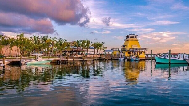 A waterfront hotel with a prominent yellow tower, docked boats, and a calm water body. - Only 2.5 miles to Beach + Heated Saltwater Pool Included! (Englewood)