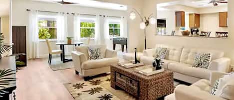 A spacious living room with a large sofa set, a coffee table, and a dining area with a table and chairs.