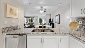 A kitchen with white cabinets, a granite countertop, and a ceiling fan. - Carlsbad Hideaway. Pool, Spa, BBQ. Walking to restaurants/shops (Carlsbad)