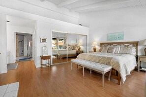 A spacious bedroom with a large bed, a bench, a mirror, and a view of the outside. - Carlsbad Hideaway. Pool, Spa, BBQ. Walking to restaurants/shops (Carlsbad)