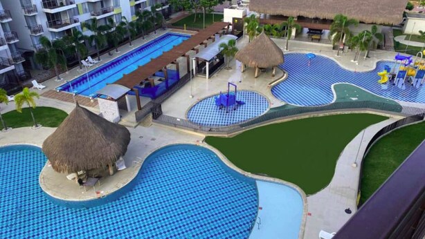 A resort with multiple swimming pools, including a large central pool and smaller pools with thatched roofs.