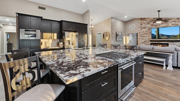 A modern kitchen with dark cabinets, a large island, and a built-in oven. - Luxury Home, Beautiful Neighborhood, Spacious for Family, with Pool/Spa.  (Glendale)