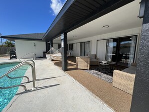Une terrasse extérieure moderne dotée d’une piscine, d’un espace salon et d’une partie abritée.