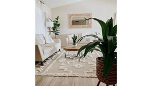 A living room with a beige sofa, a coffee table, and a large potted plant. - Malvia’s Oasis- Cozy home with a Private Pool (Englewood)