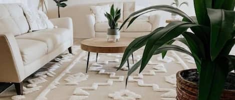 A living room with a beige sofa, a coffee table, and a large potted plant.