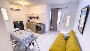 Een kleine leefruimte met een kitchenette, een eethoek en een bank.