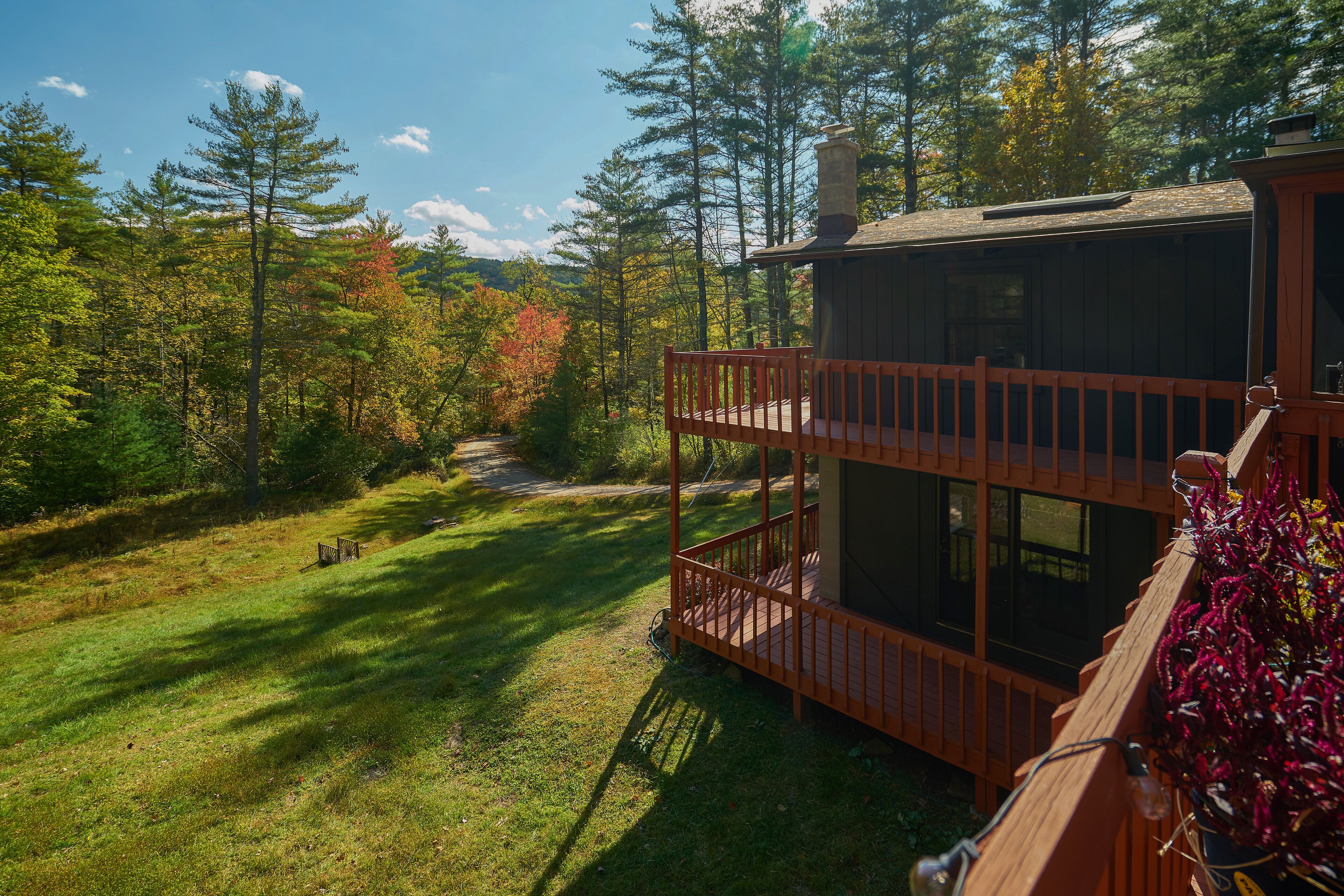 A cabin with a wooden deck and a view of a forested area.