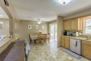 A kitchen with wooden cabinets, a dining area with a table and chairs, and a ceiling fan.
