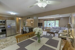 A spacious living area with a dining table, sofa, and a ceiling fan.