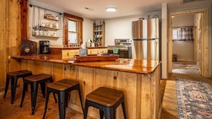 A kitchen with wooden cabinetry, a central island with stools, and a refrigerator. - Hike the Holler - Stay & Explore (Cosby)