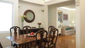 Un comedor con una mesa y sillas de madera, un florero con flores y un espejo en la pared.