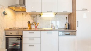 Eine moderne Küche mit weißen Schränken, einem eingebauten Backofen, einer Spülmaschine und einem Gasherd.