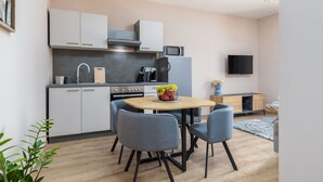 A modern kitchen with white cabinets, a microwave, a stove, and a dining area with a table and chairs.