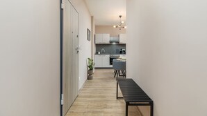 A narrow hallway with a wooden floor leading to a kitchen area with white cabinets and a dining table. - Marceta Apartment 3 - Pool and Big Garden (Fažana)