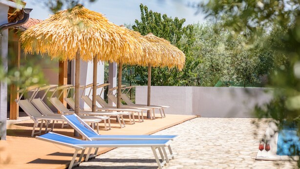 A poolside area with sun loungers and thatched umbrellas. - Marceta Apartment 3 - Pool and Big Garden (Fažana)