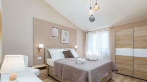A bedroom with a bed, bedside tables, a lamp, and a nightstand. - Marceta Apartment 3 - Pool and Big Garden (Fažana)