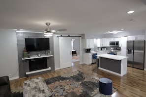 Enjoy a spacious living area with a large flat-screen TV and central island, perfect for dining or working.