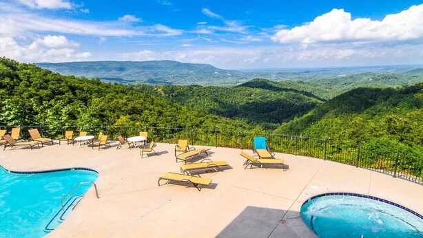A pool area with lounge chairs and a view of a mountainous landscape. - 2BD/Sevierville - Smoky Mountains Resort w/pools! (Sevierville)
