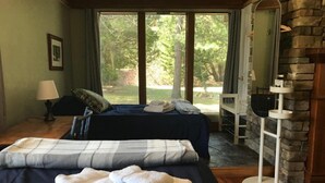 Un dormitorio con cama, mesita de noche, lámpara, chimenea y vistas al exterior.