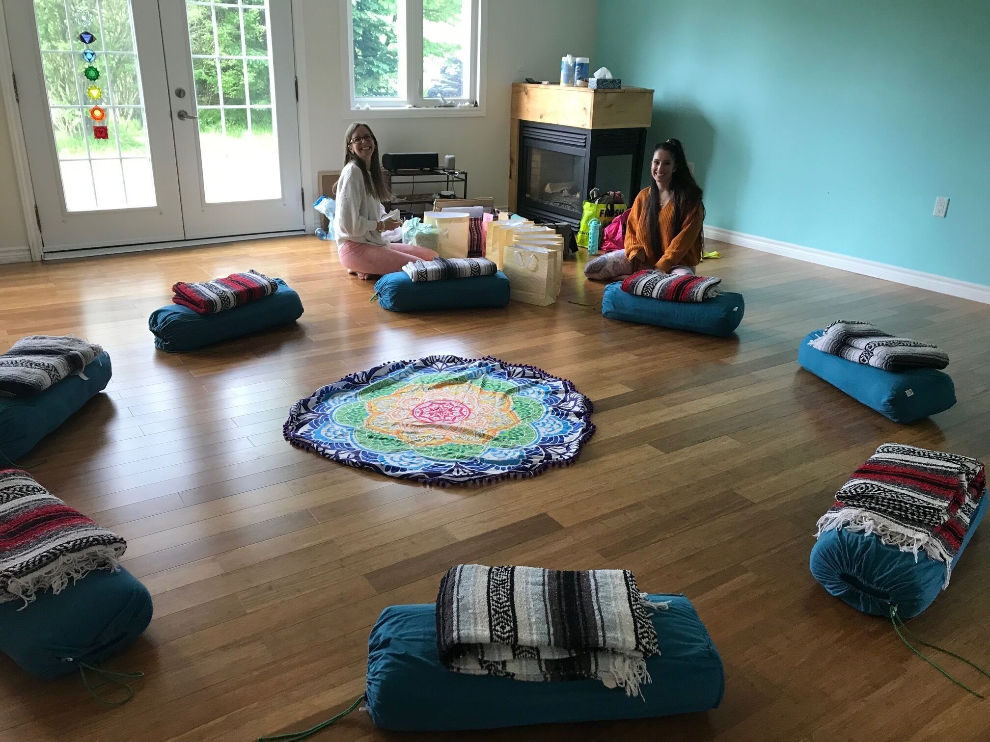 A room with a wooden floor, a central round rug, and several blue bean bag chairs.