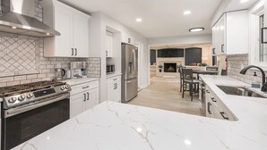 A modern kitchen with white cabinetry, a stainless steel range, and a marble countertop. - Family Retreat with Hot Tub & EV (Avon Lake)
