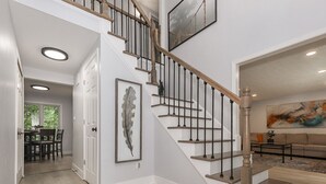 A staircase with wooden steps and black balusters, leading to an upper floor. - Family Retreat with Hot Tub & EV (Avon Lake)