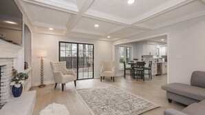 A spacious living room with a fireplace, a dining area, and a kitchen in the background. - Family Retreat with Hot Tub & EV (Avon Lake)