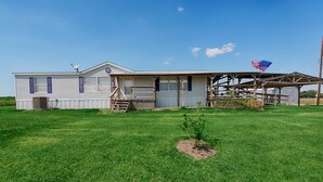 A single-story mobile home with a porch and a small garden.