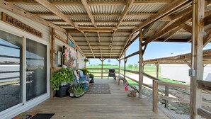 A covered porch with wooden flooring, a bench, and potted plants.