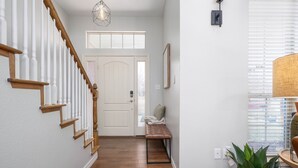A hallway with a wooden staircase, a bench, a door, and a potted plant. - The West Nest 2 -Families, 2 Kings, Game Room (Canyon)
