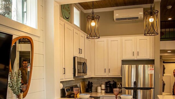 Una cocina moderna con armarios blancos, electrodomésticos de acero inoxidable y dos taburetes de bar.