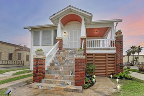 Una casa a due piani con un portico, una scala con piastrelle decorative e un garage.