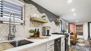 Una cocina moderna con encimera blanca, electrodomésticos de acero inoxidable y salpicadero de azulejos hexagonales.
