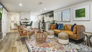 Una sala de estar moderna con un sofá de cuero, una silla de madera y un tapete colorido.